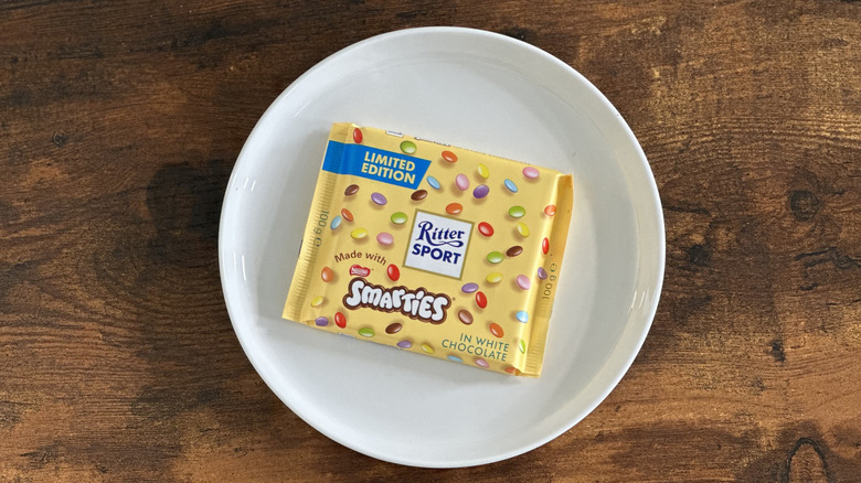 package of Ritter Sport White Chocolate with Smarties on white plate on wooden table
