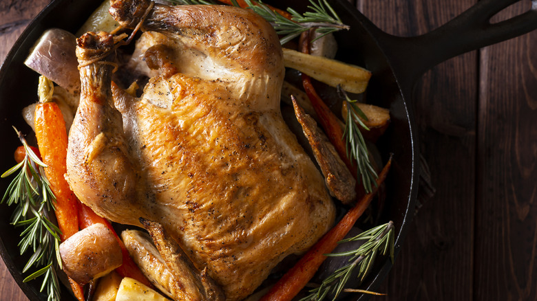 Roast chicken with rosemary and carrots in cast iron