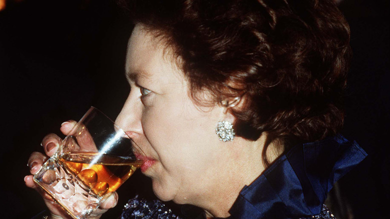 A close-up of Princess Margaret sipping on a glass of whisky