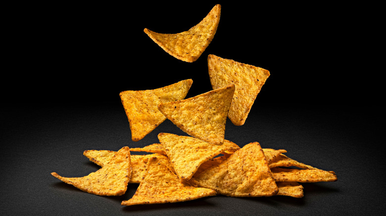 Tortilla chips falling on black background