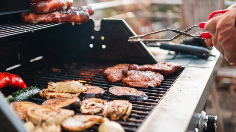 Meat and veggies cooking on gas grill